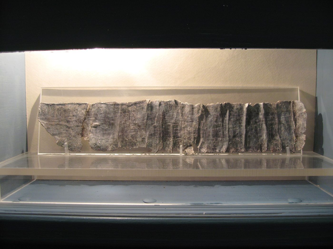A thin rectangular sheet of grey lead covered in small scratched Greek letters.