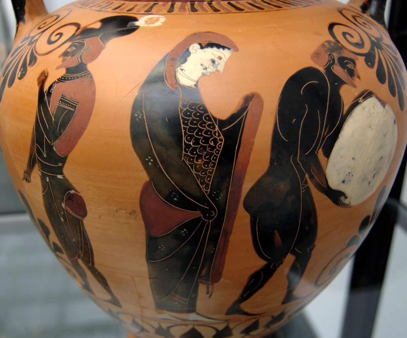 A Greek black-figure vase painting of the underworld, with a bearded figure bent forward pushing a large white boulder.