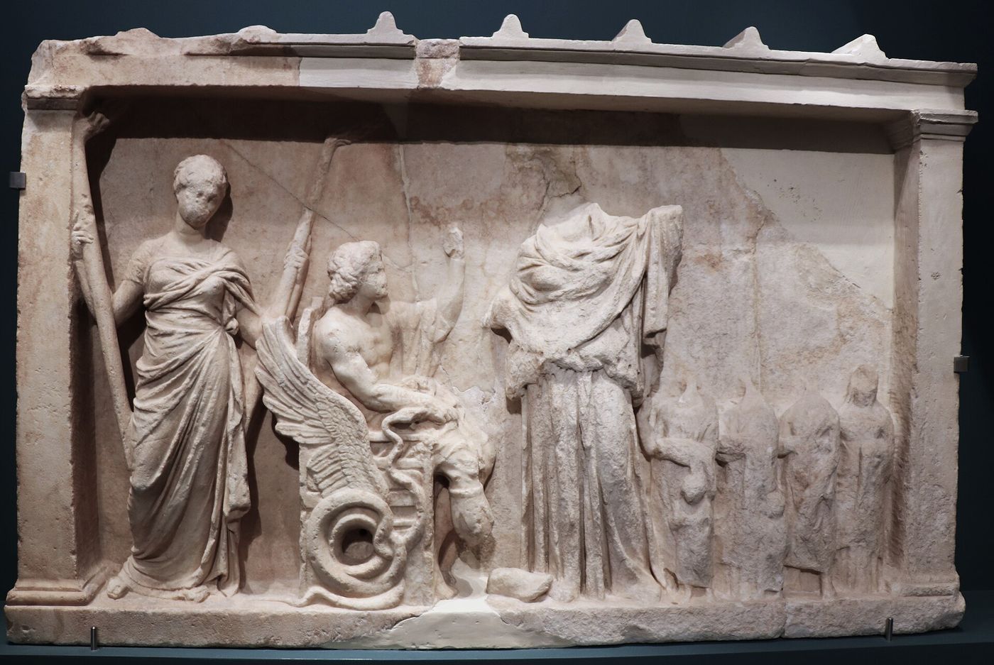 A votive marble relief from Eleusis depicting Demeter, Persephone and Triptolemos with sheaves of grain.