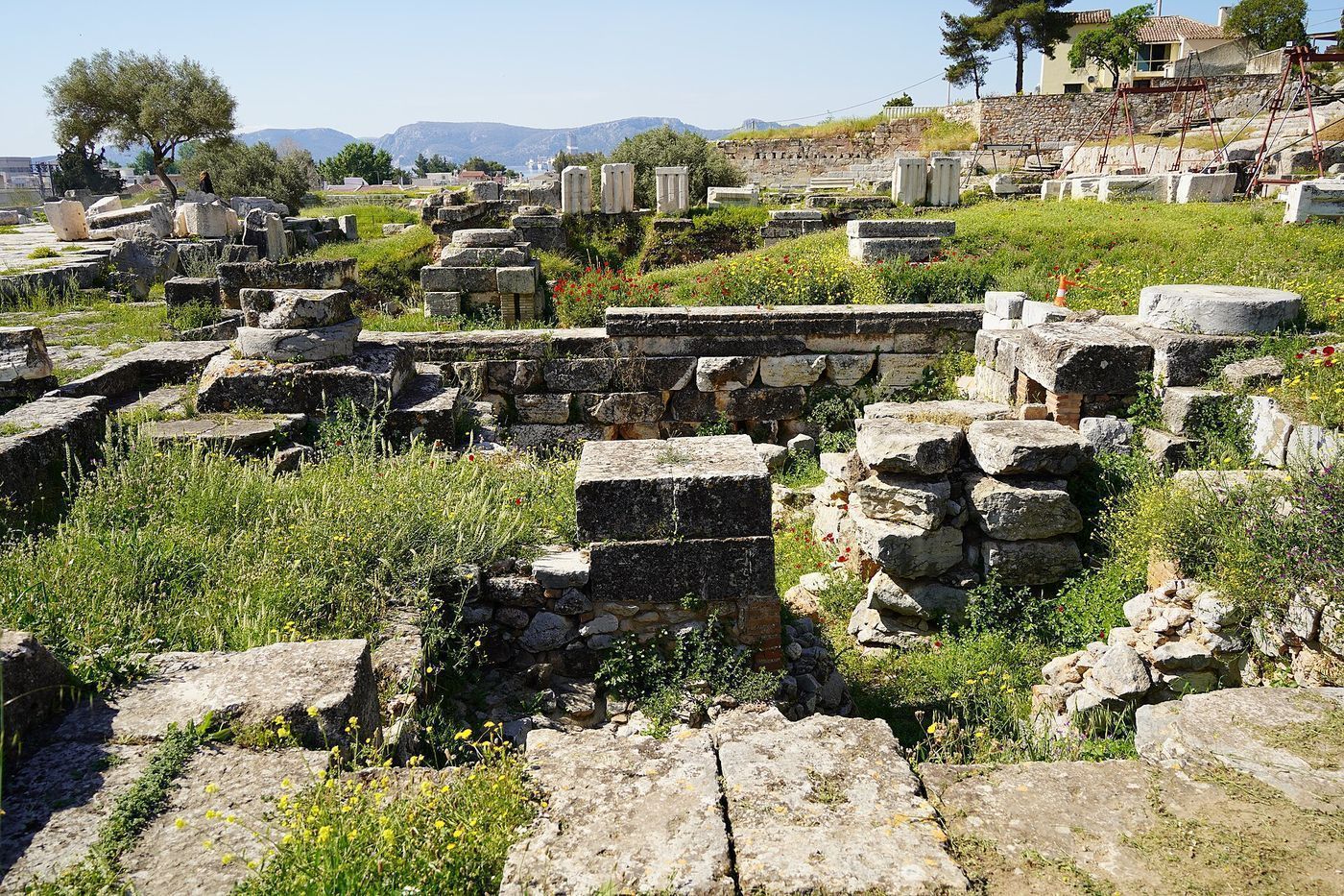 The excavated foundations of the Telesterion at Eleusis, a large square hall cut into a rocky hillside.