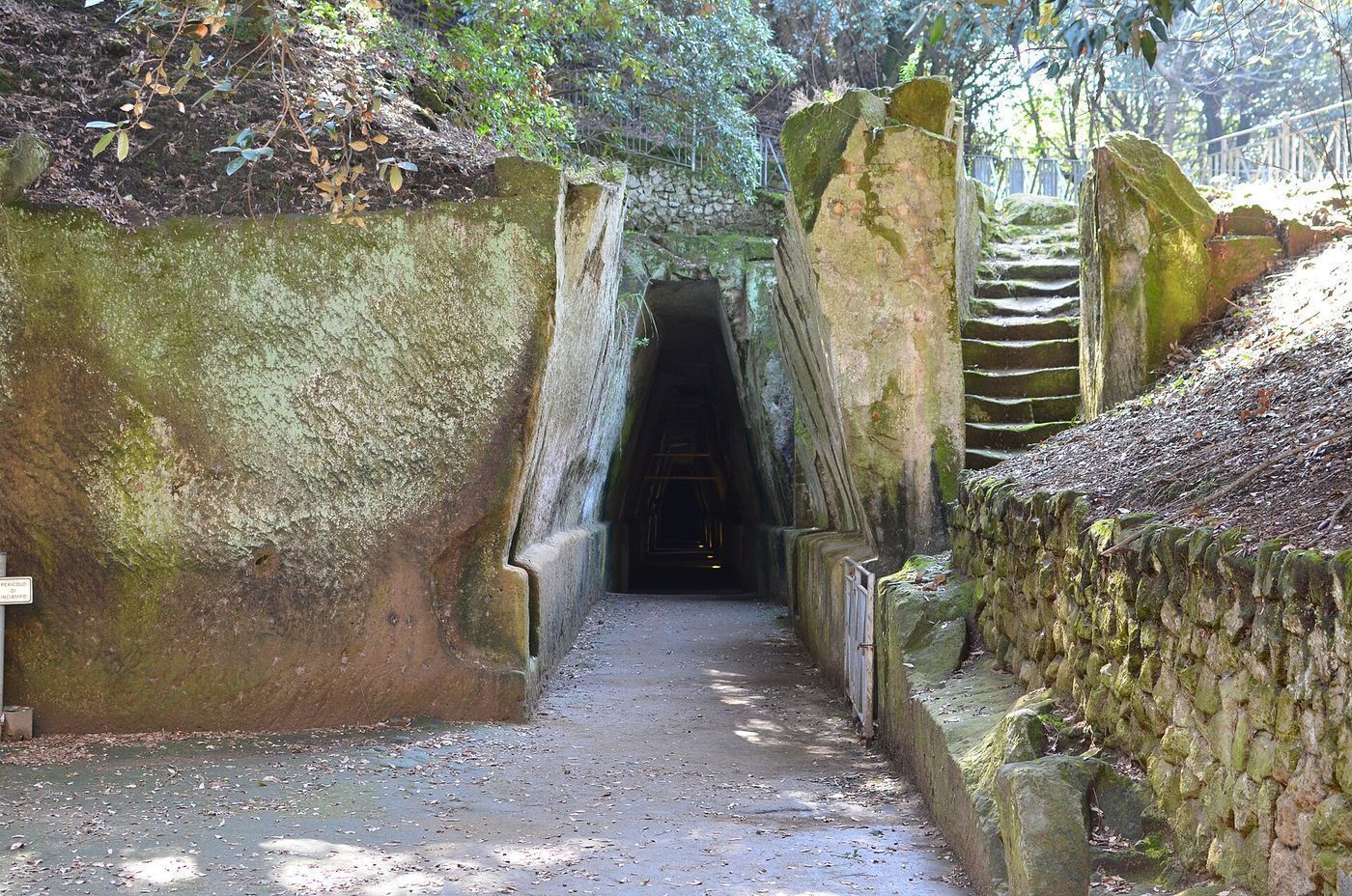 A long trapezoidal rock-cut corridor at Cumae, lit by openings along one side, receding into darkness.